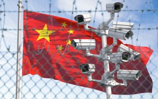 Flag of China behind barbed wire fence and cctv cameras.